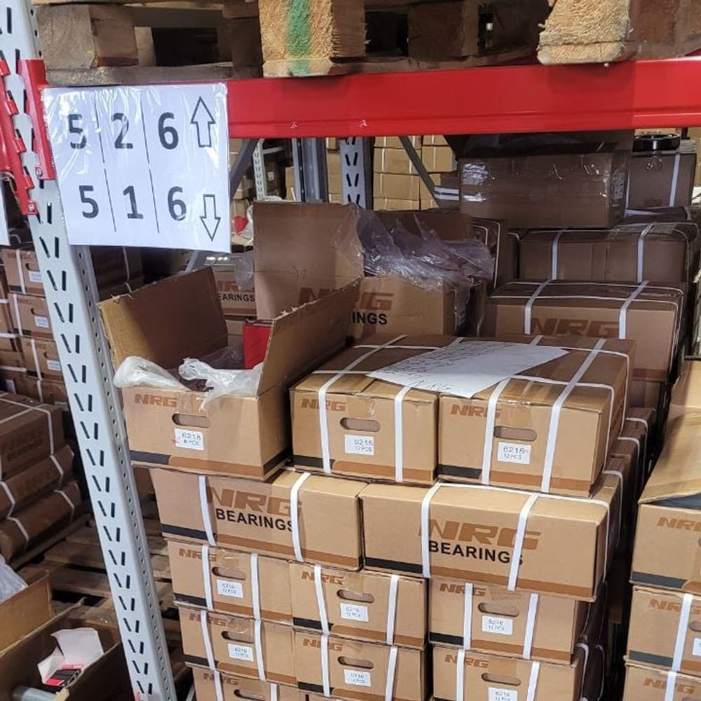 Warehouse racking stacked with boxed bearings, every pallet position labelled.