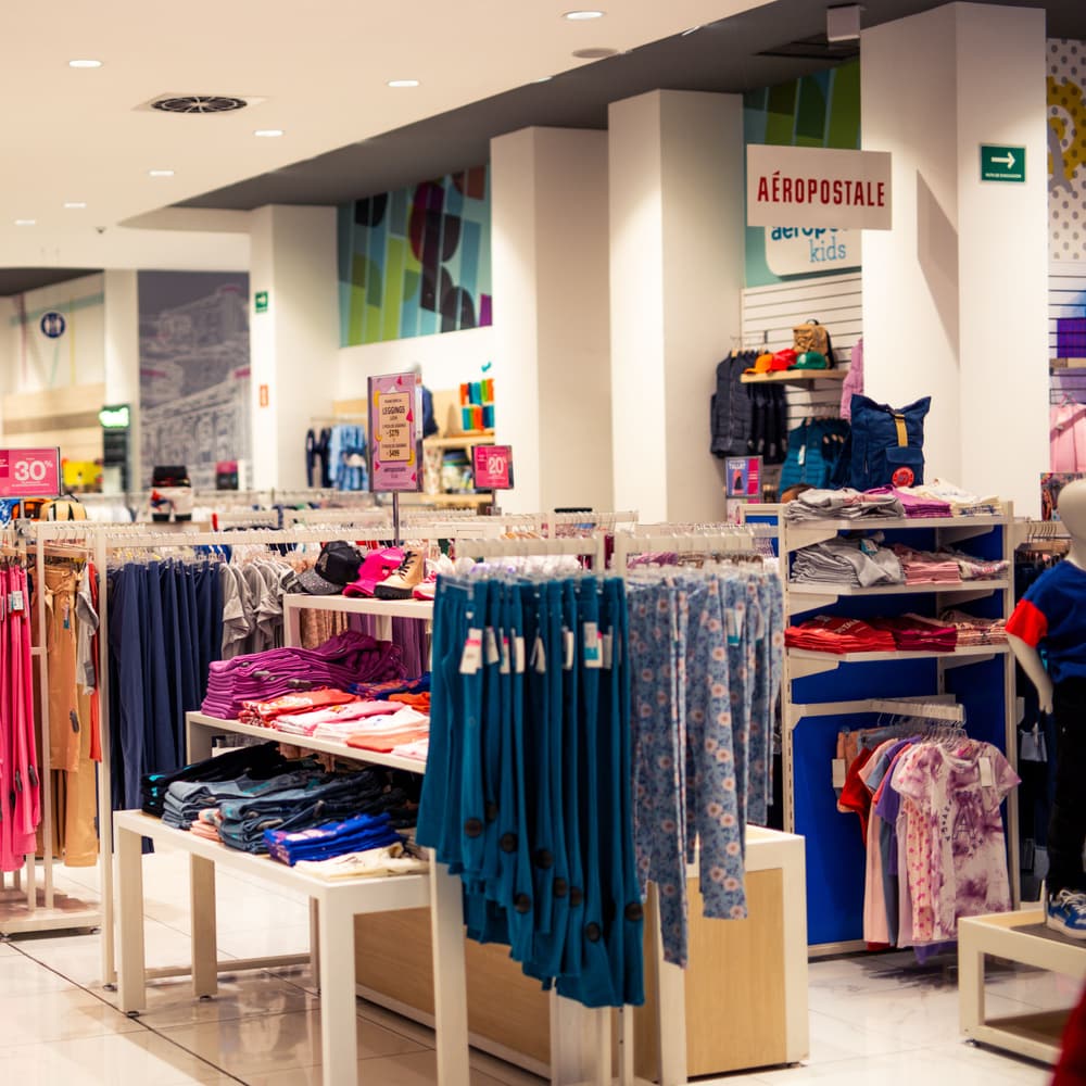 Clothing laid out on rails and display tables in a retail store.